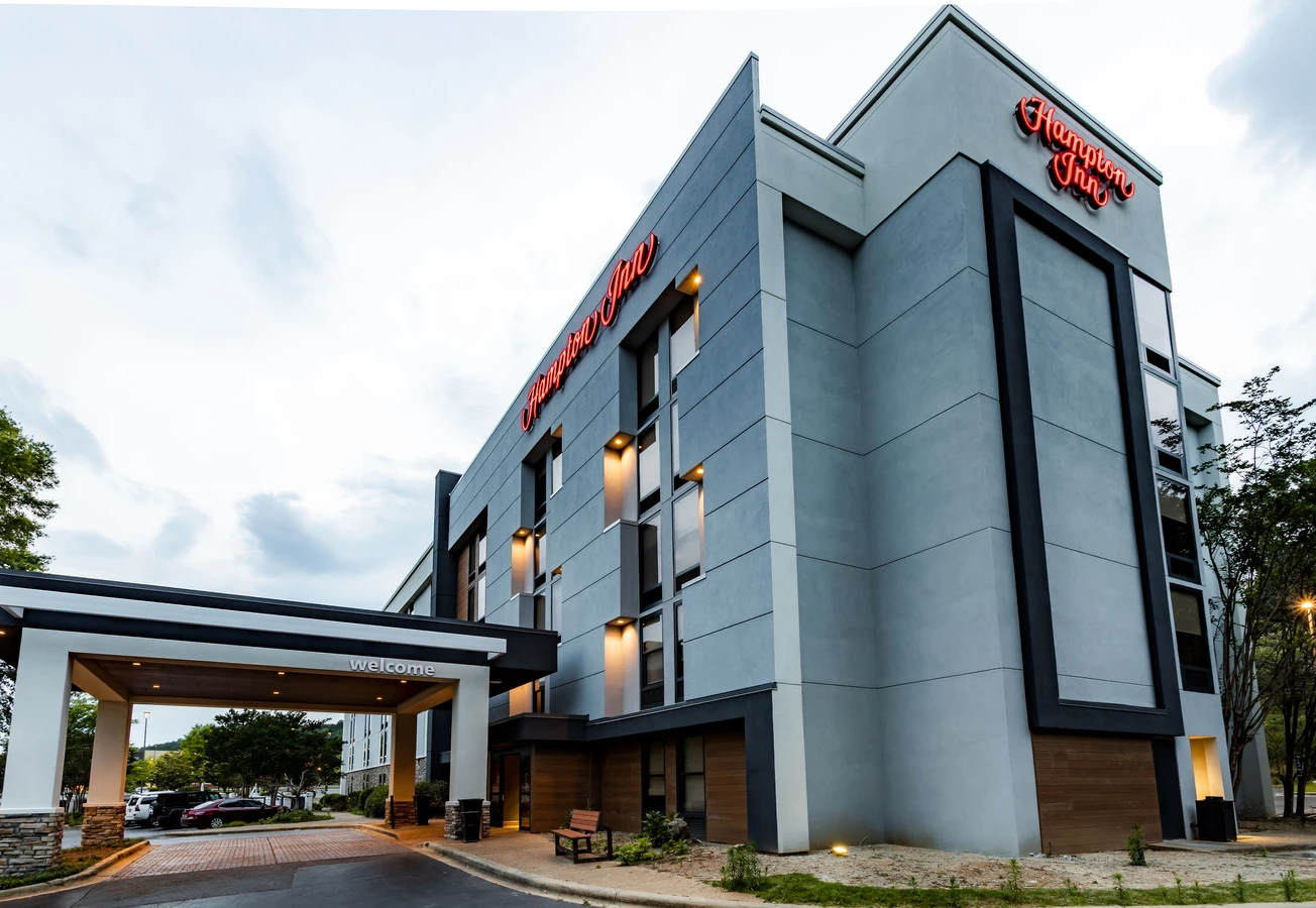 hampton inn exterior hotel renovation in birmingham alabama that enhanced curb appeal with architectural elements, color blocking, faux wood, upgraded porte cochere, eifs repair and more - the photo depicts the upgrades made to the hotel